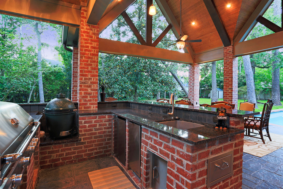 Inspiration for a craftsman backyard stamped concrete patio kitchen remodel in Houston with a roof extension
