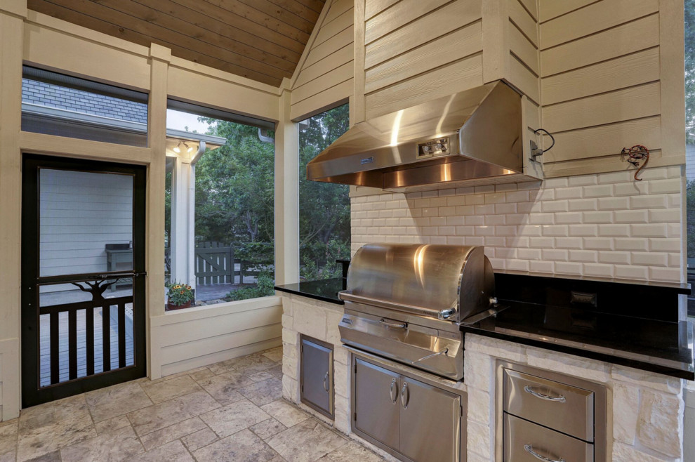 Cette photo montre une terrasse arrière chic de taille moyenne avec une cuisine d'été, des pavés en pierre naturelle et une extension de toiture.