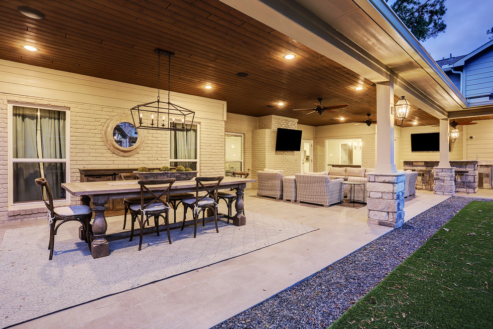 Cette image montre une grande terrasse arrière traditionnelle avec une cuisine d'été, du carrelage et une extension de toiture.
