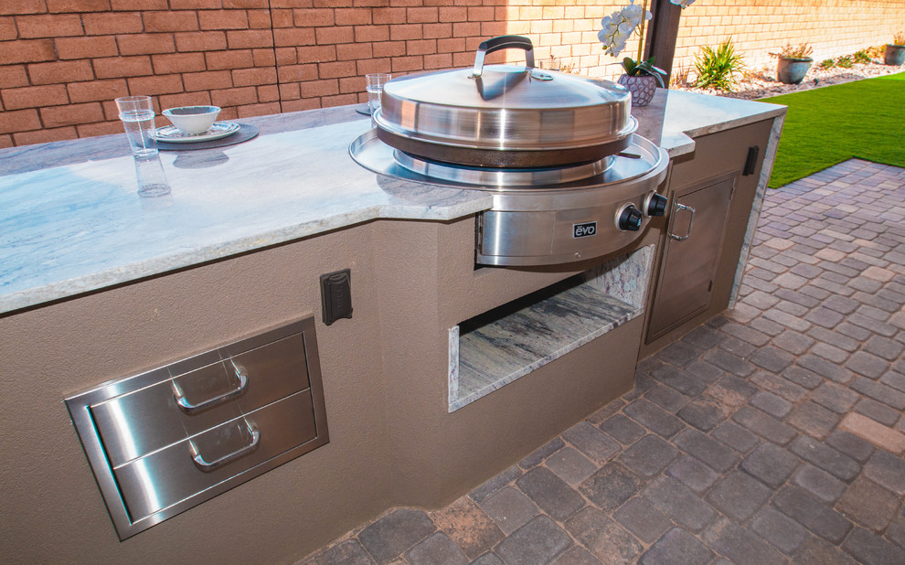 This is an example of a large contemporary back patio in Las Vegas with an outdoor kitchen, brick paving and an awning.
