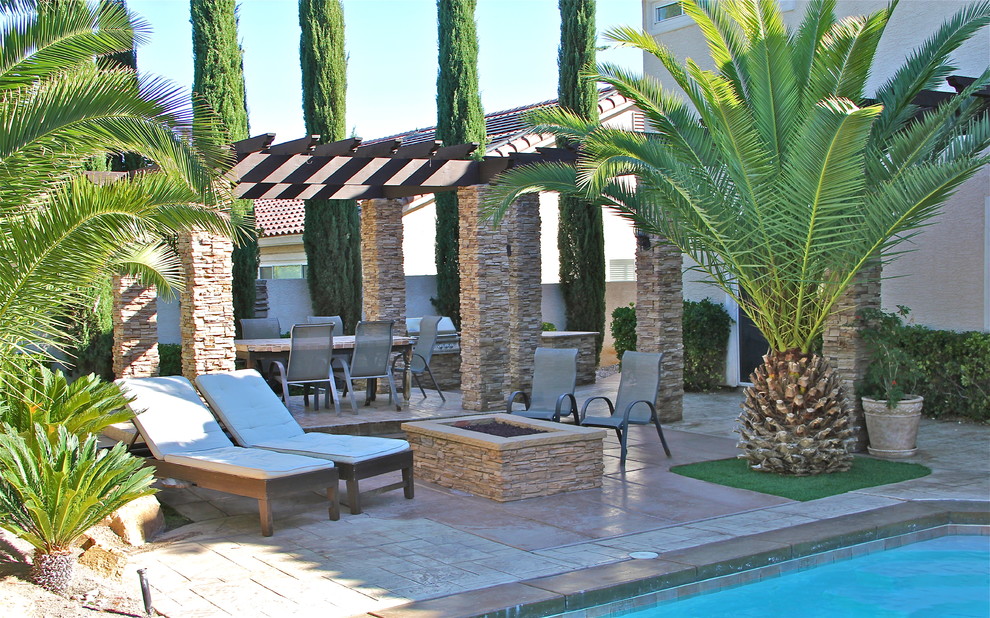 Esempio di un ampio patio o portico mediterraneo dietro casa con un focolare, pavimentazioni in cemento e una pergola