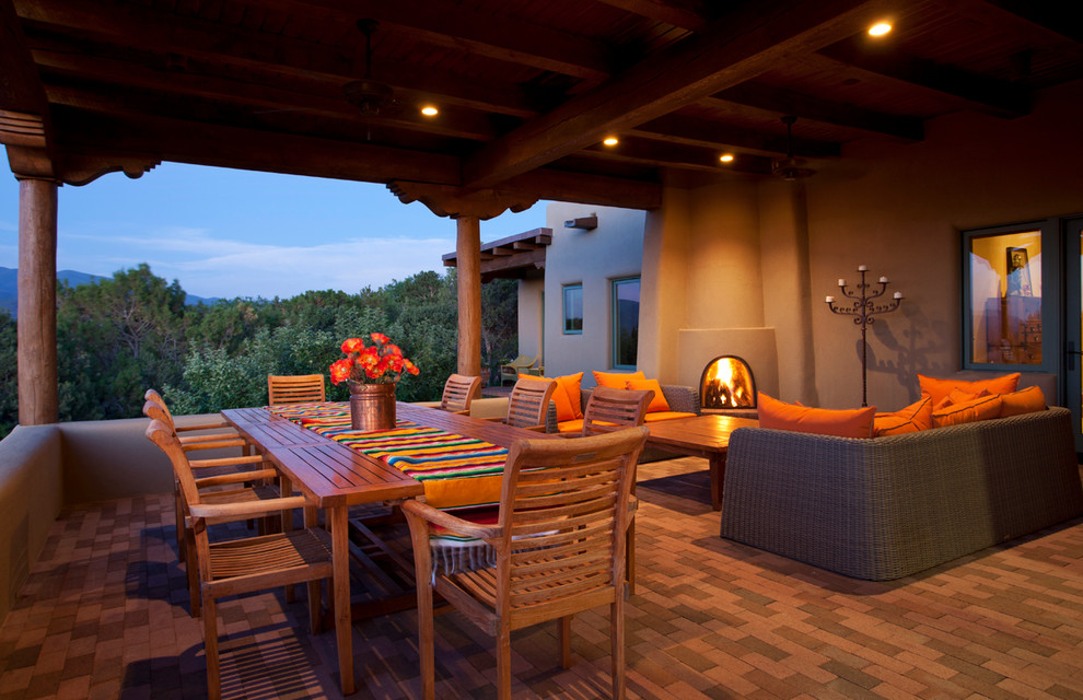 Inspiration for a medium sized mediterranean back patio in Albuquerque with a fire feature, brick paving and a roof extension.
