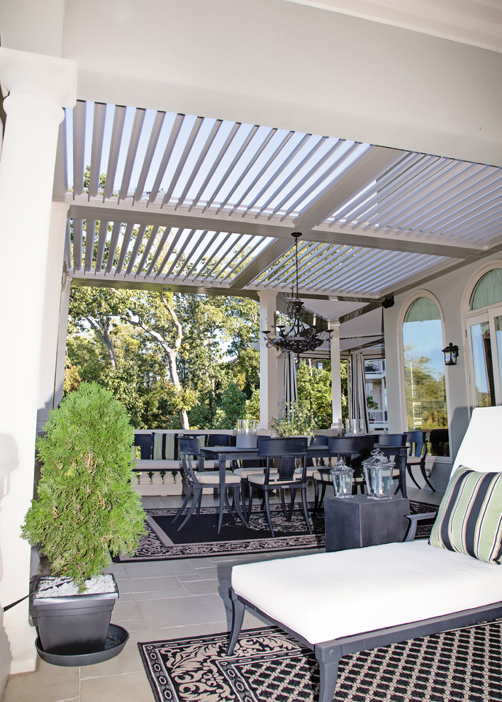 Idee per un patio o portico tropicale dietro casa con piastrelle e un parasole