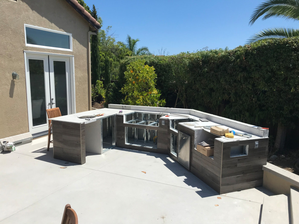 Example of a mid-sized minimalist backyard concrete patio kitchen design in San Diego with a pergola