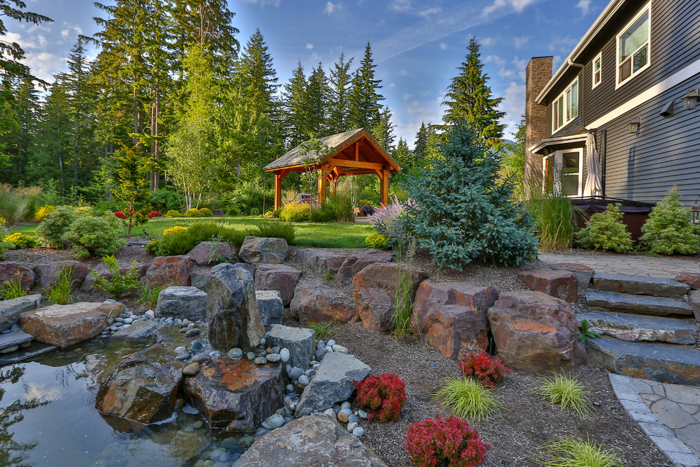 Inspiration for a large craftsman backyard stone patio fountain remodel in Seattle with a gazebo