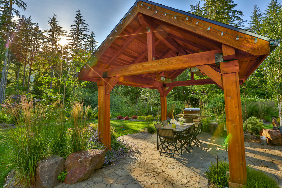 Large traditional back patio in Seattle with a water feature, natural stone paving and a gazebo.