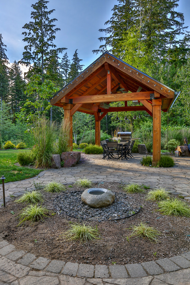 Ejemplo de patio de estilo americano grande en patio trasero con fuente, adoquines de piedra natural y cenador