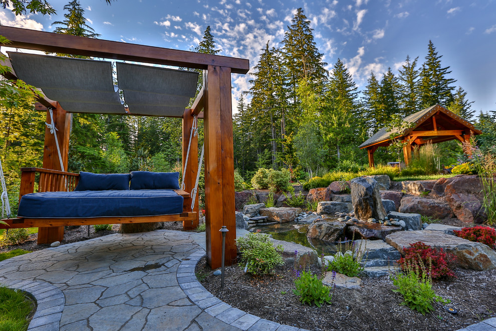 Foto de patio de estilo americano grande en patio trasero con fuente, adoquines de piedra natural y cenador