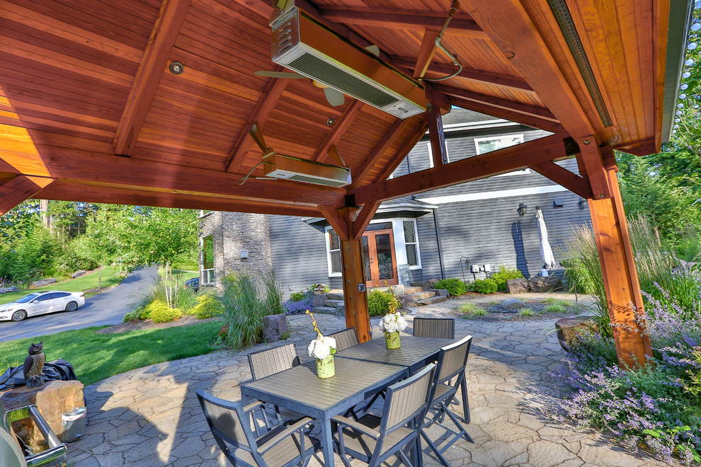 Photo of a large classic back patio in Seattle with a water feature, natural stone paving and a gazebo.