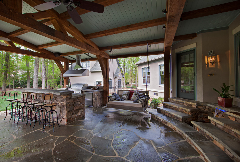 Diseño de patio tradicional grande en patio trasero y anexo de casas con cocina exterior y adoquines de piedra natural