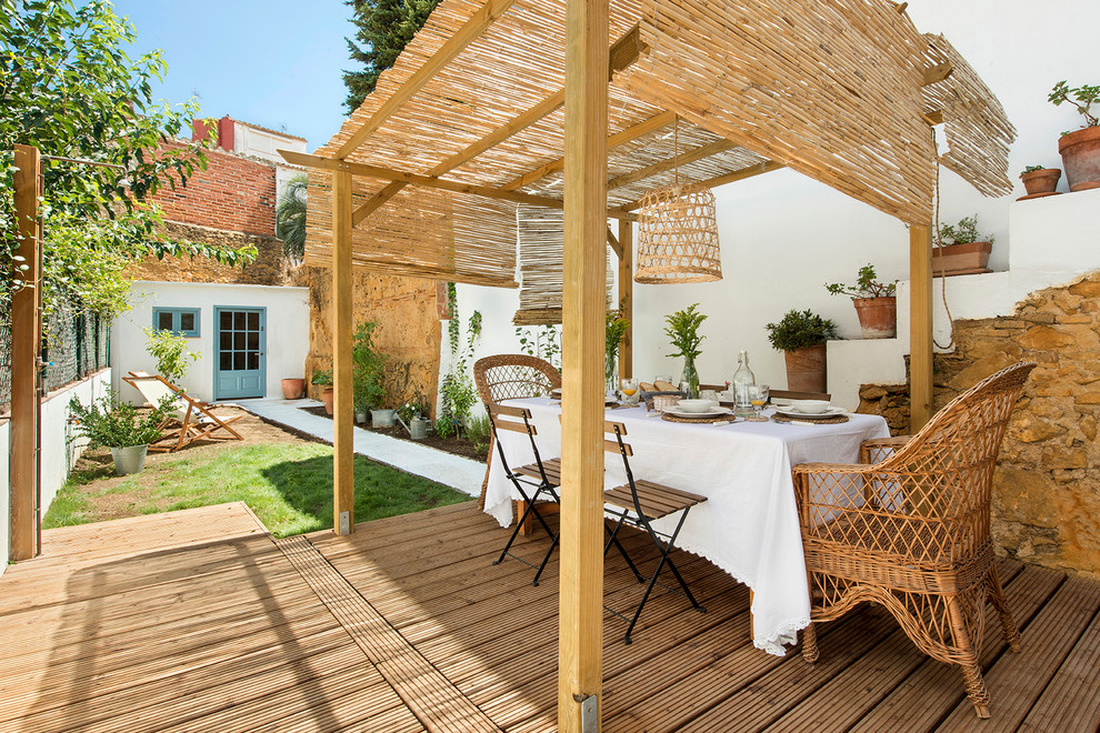 Imagen de patio mediterráneo de tamaño medio en patio trasero con jardín de macetas, entablado y toldo