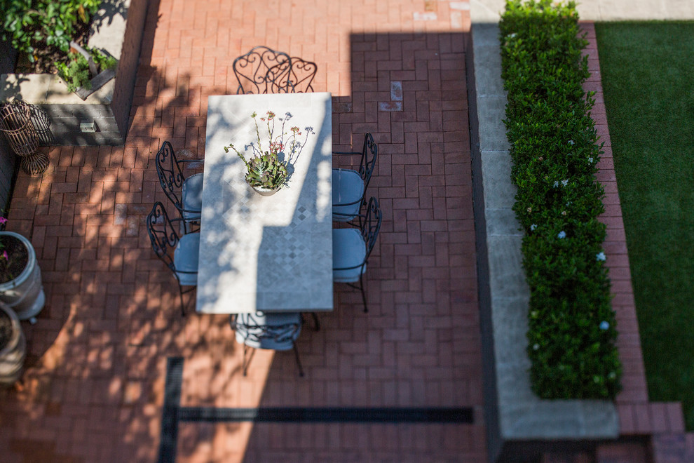 На фото: большой двор на заднем дворе в современном стиле с мощением клинкерной брусчаткой без защиты от солнца