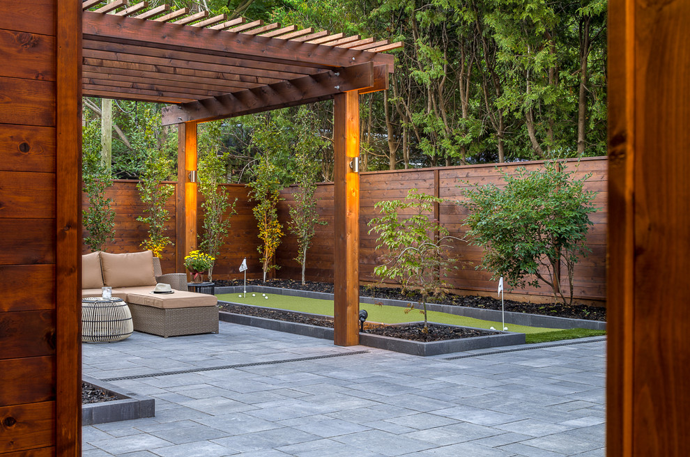 Idée de décoration pour une terrasse arrière design de taille moyenne avec des pavés en pierre naturelle et une pergola.