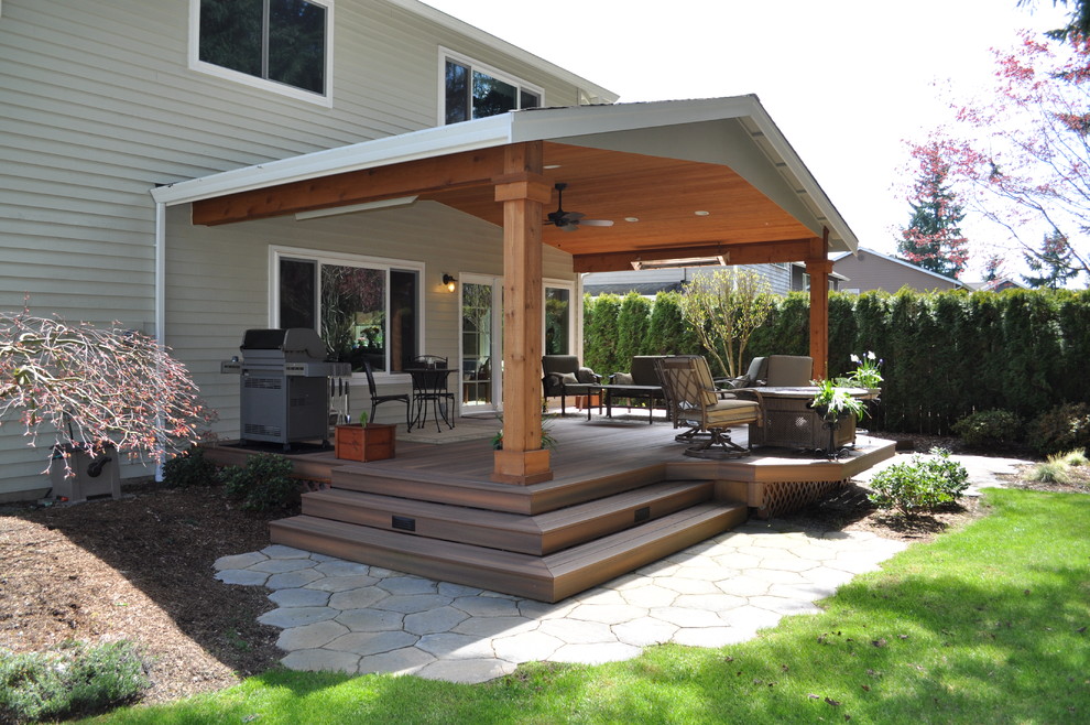 Exemple d'une terrasse arrière chic de taille moyenne avec un foyer extérieur, des pavés en béton et un auvent.