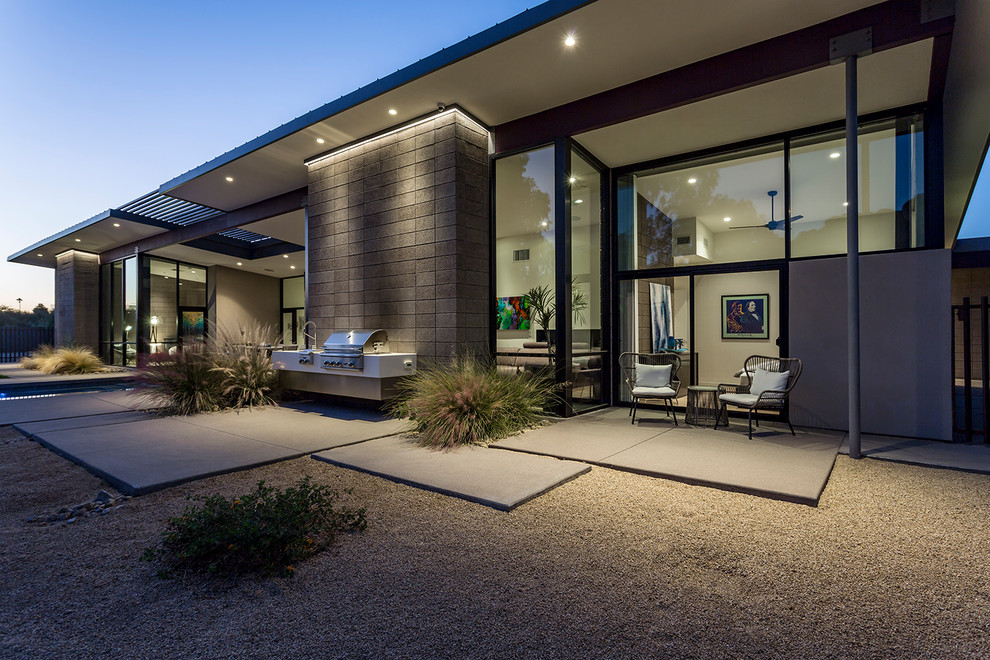 Foto di un patio o portico minimalista dietro casa con lastre di cemento e un tetto a sbalzo