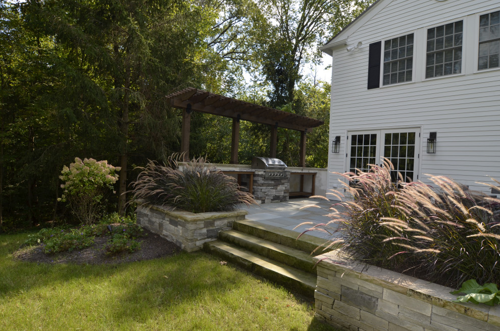Große Klassische Pergola hinter dem Haus mit Outdoor-Küche und Natursteinplatten in Cleveland