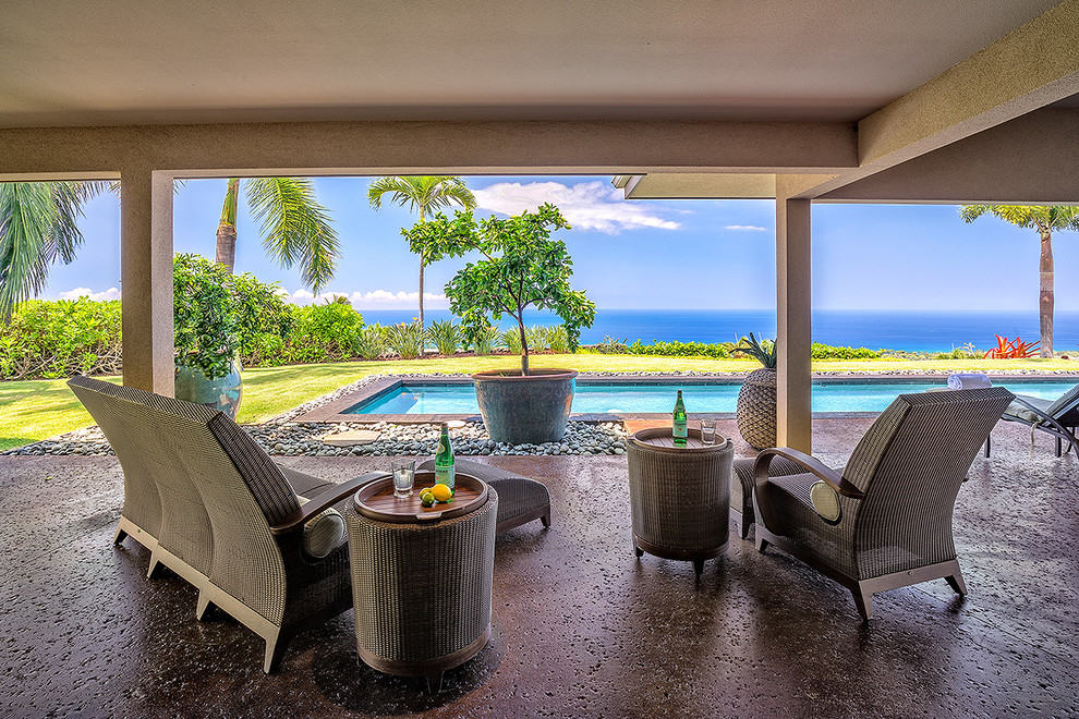 Photo of a large contemporary back patio in Hawaii with concrete slabs and a roof extension.
