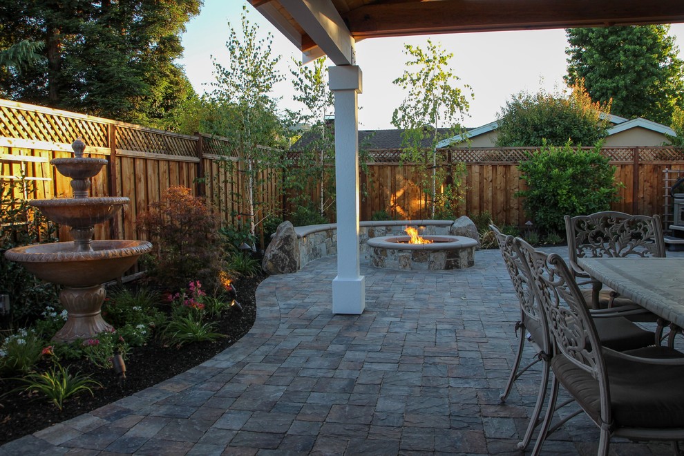 Esempio di un patio o portico american style dietro casa con pavimentazioni in pietra naturale, un focolare e una pergola