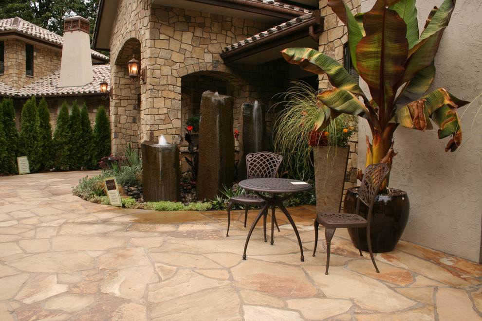 Idee per un patio o portico mediterraneo dietro casa con pavimentazioni in pietra naturale, nessuna copertura e fontane