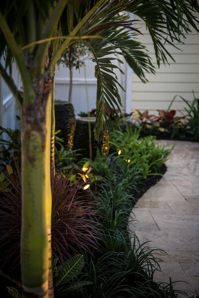 Inspiration for a small tropical courtyard stone patio fountain remodel in Miami with a pergola