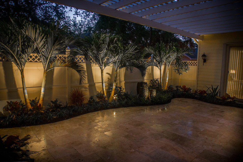 Diseño de patio tropical pequeño en patio con fuente, adoquines de piedra natural y pérgola