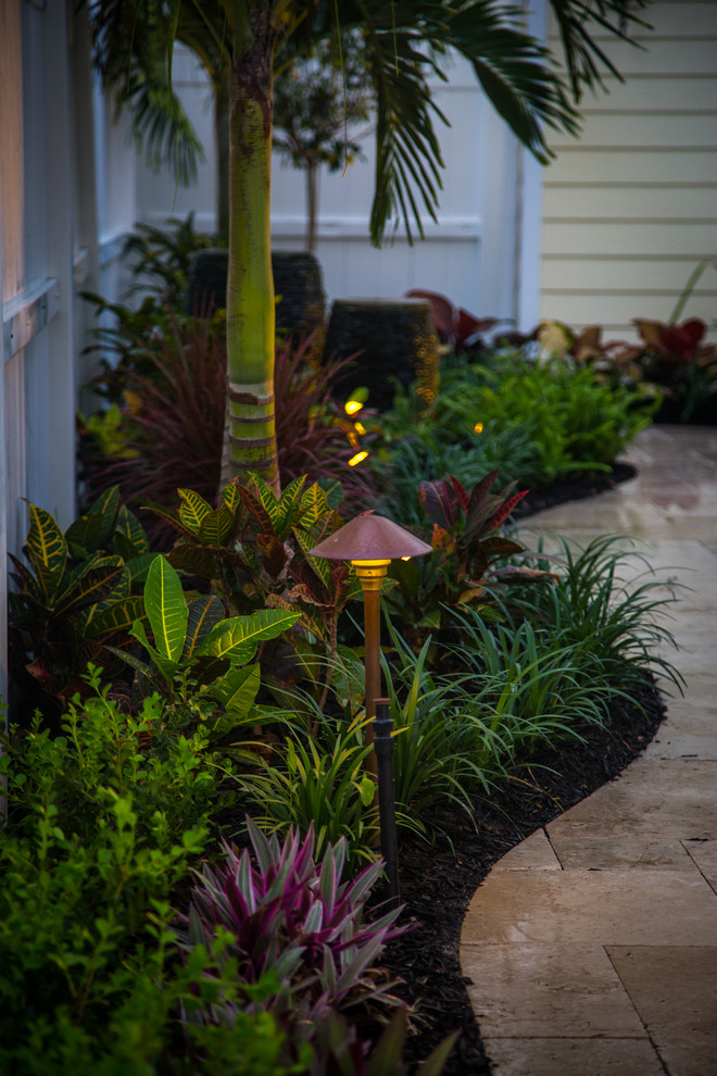Example of a small island style courtyard stone patio fountain design in Miami with a pergola