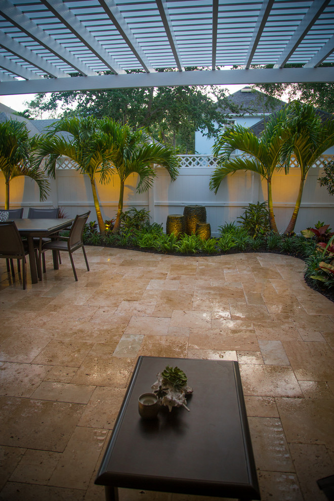 Esempio di un piccolo patio o portico tropicale in cortile con fontane, pavimentazioni in pietra naturale e una pergola