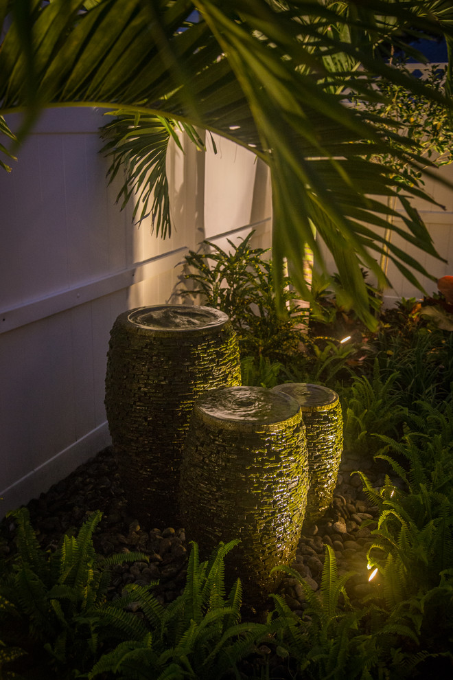 マイアミにある小さなトロピカルスタイルのおしゃれな中庭のテラス (噴水、天然石敷き、パーゴラ) の写真
