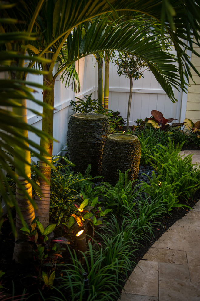 Immagine di un piccolo patio o portico tropicale in cortile con fontane, pavimentazioni in pietra naturale e una pergola