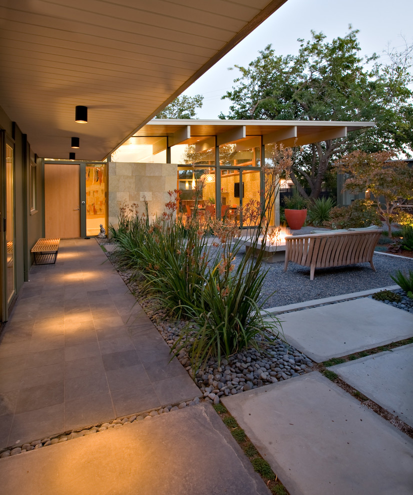 Cette image montre une terrasse vintage avec un foyer extérieur, une cour, des pavés en béton et une extension de toiture.