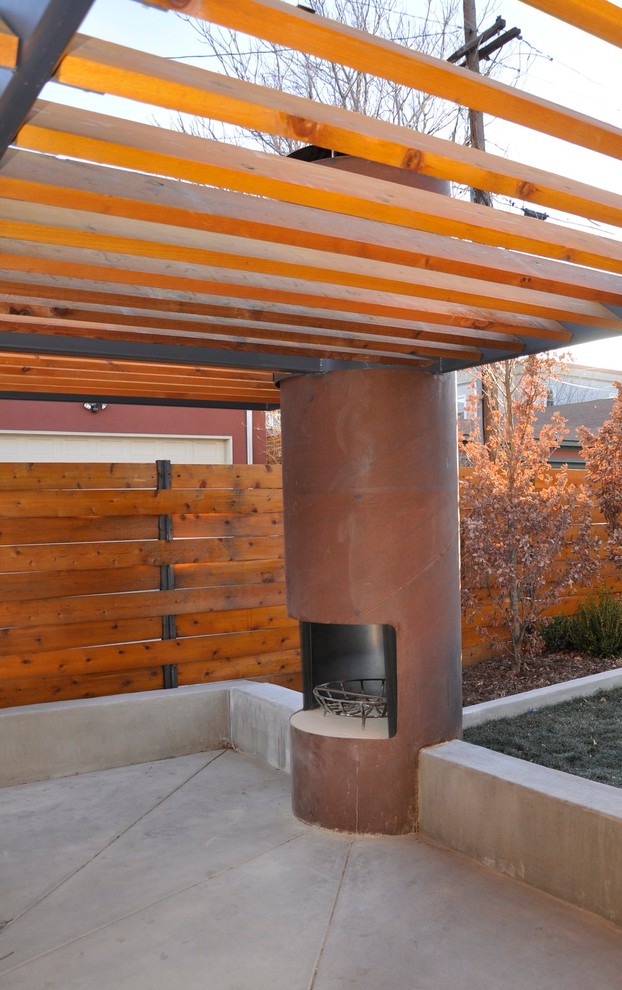Cette image montre une grande terrasse arrière minimaliste avec un foyer extérieur et une pergola.