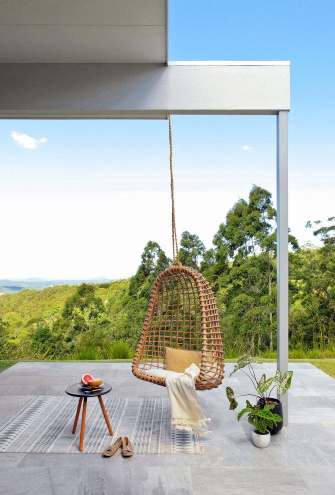 Inspiration pour une terrasse arrière minimaliste de taille moyenne avec du carrelage et une extension de toiture.