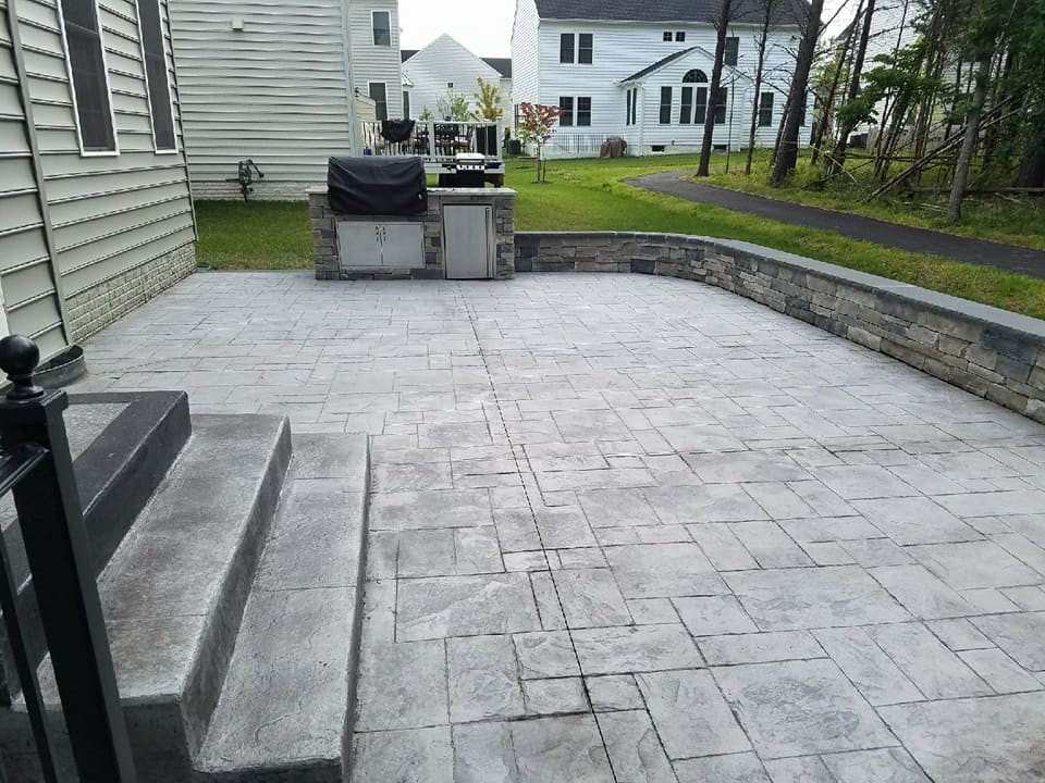 Photo of a large classic back patio in Other with an outdoor kitchen, stamped concrete and no cover.