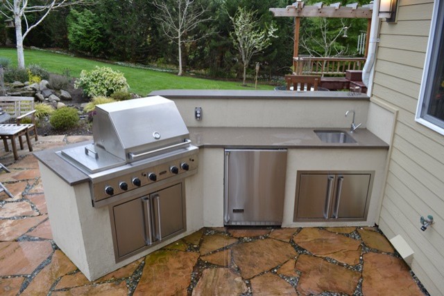 Photo of a small eclectic back patio in Seattle with an outdoor kitchen, natural stone paving and an awning.