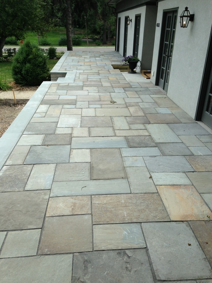 Large traditional front patio in Minneapolis with natural stone paving.