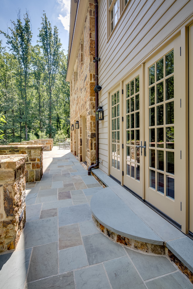 Idee per un ampio patio o portico country dietro casa con pavimentazioni in pietra naturale e nessuna copertura