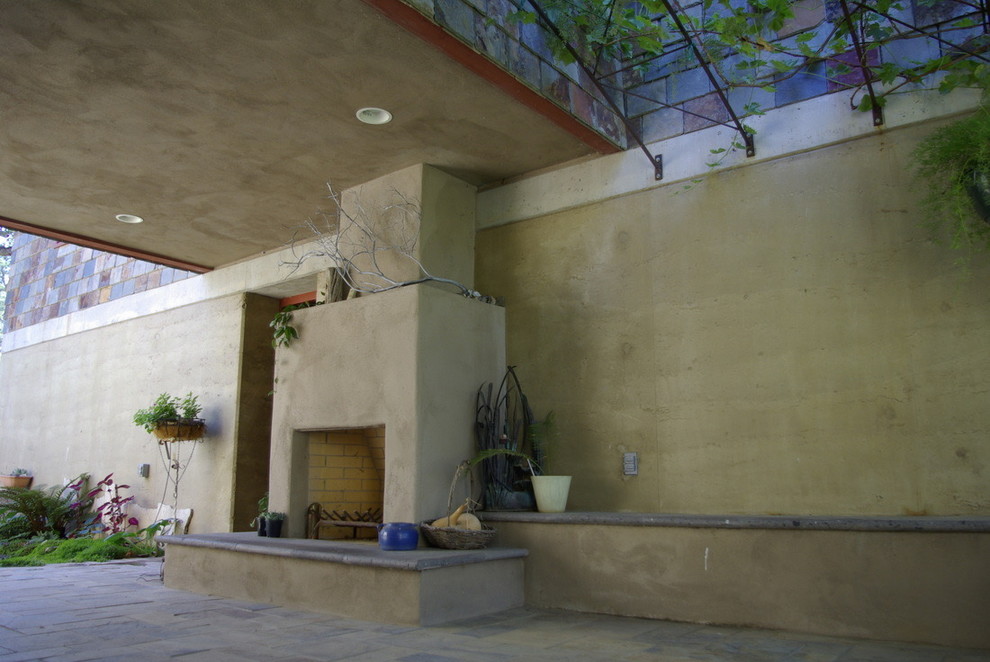 Ispirazione per un grande patio o portico rustico dietro casa con un focolare, un tetto a sbalzo e pavimentazioni in pietra naturale