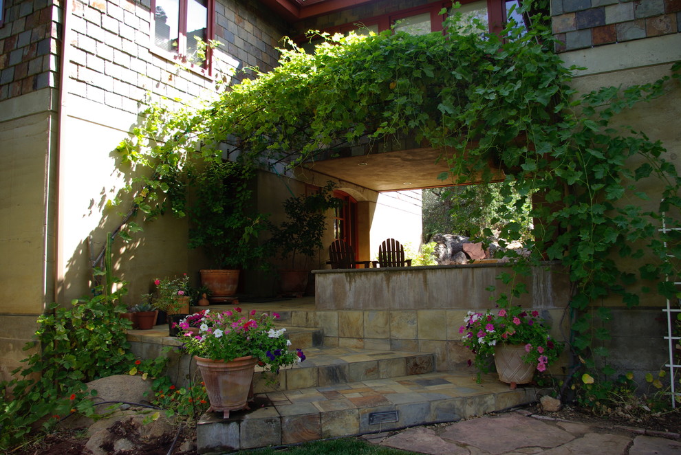 他の地域にある高級な広いラスティックスタイルのおしゃれな裏庭のテラス (張り出し屋根、ファイヤーピット、天然石敷き) の写真