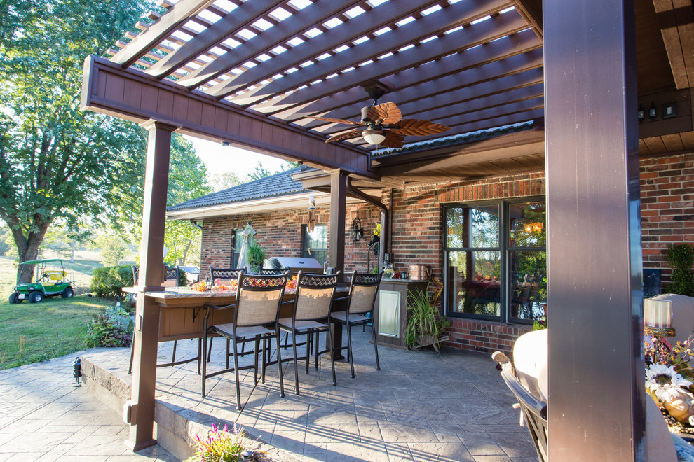 Design ideas for a large classic back patio in Kansas City with an outdoor kitchen, stamped concrete and a pergola.