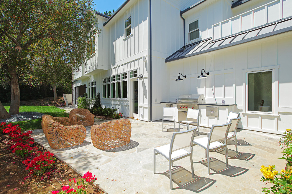 Photo of a farmhouse patio in Los Angeles with natural stone paving and an outdoor kitchen.
