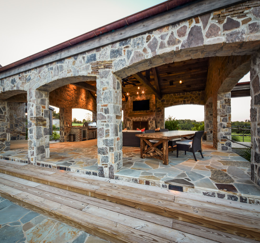 Photo of a rustic patio in Houston with natural stone paving and a roof extension.