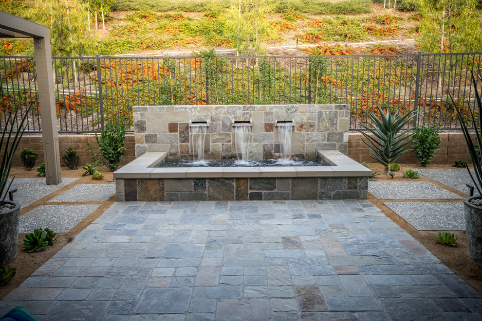 Inspiration for a large contemporary backyard stone patio remodel in Orange County with a fire pit and a pergola