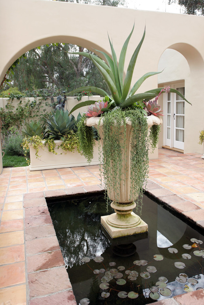 Idee per un grande patio o portico mediterraneo in cortile con un giardino in vaso, piastrelle e nessuna copertura