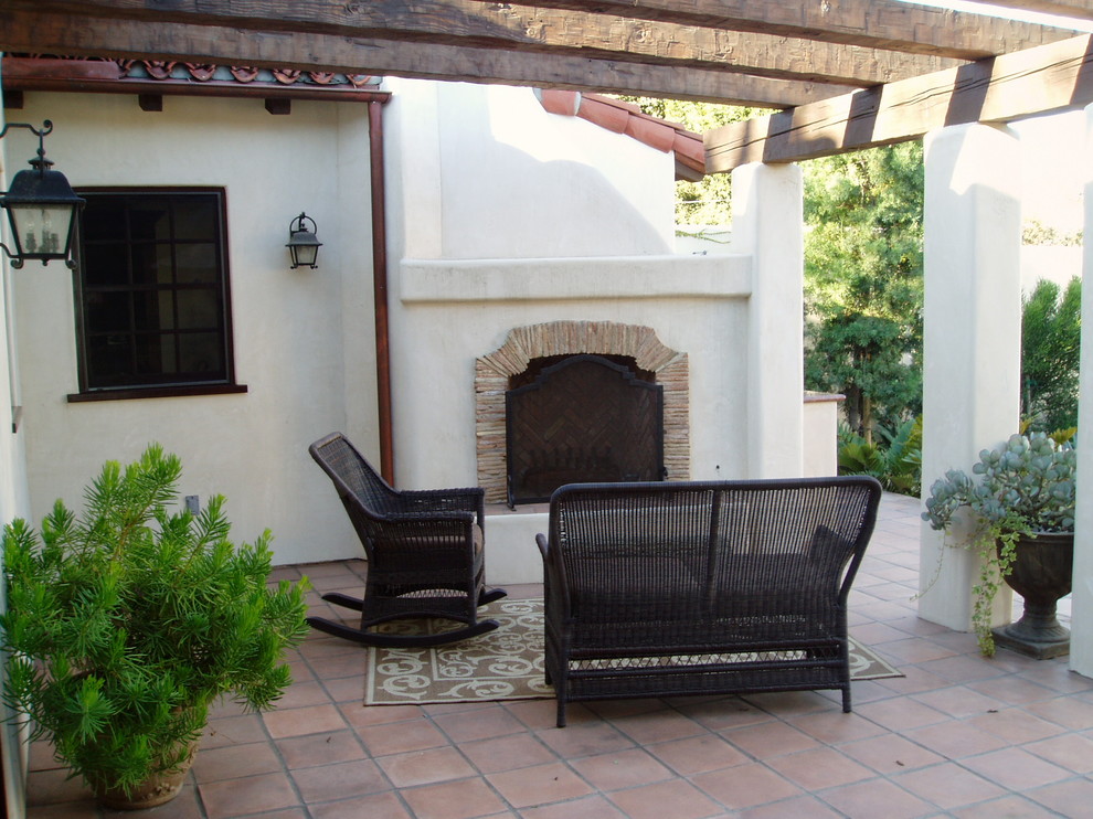 Foto di un patio o portico mediterraneo dietro casa con un caminetto e piastrelle
