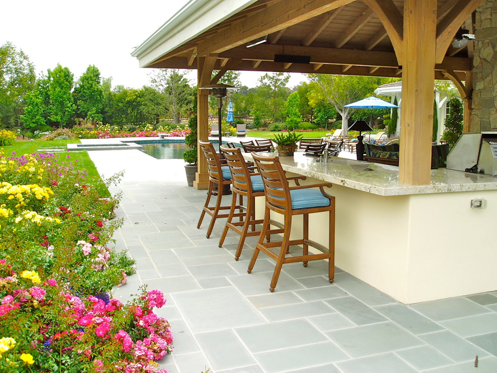 Immagine di un patio o portico tradizionale dietro casa con pavimentazioni in pietra naturale e un gazebo o capanno