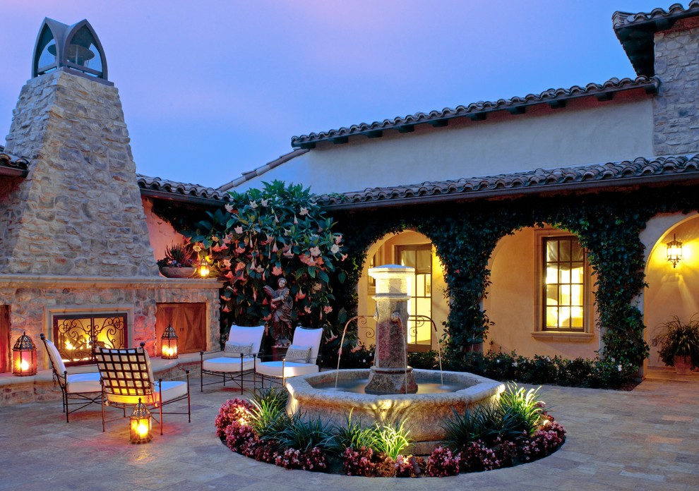 Exemple d'une terrasse avant romantique avec un foyer extérieur, des pavés en pierre naturelle et aucune couverture.