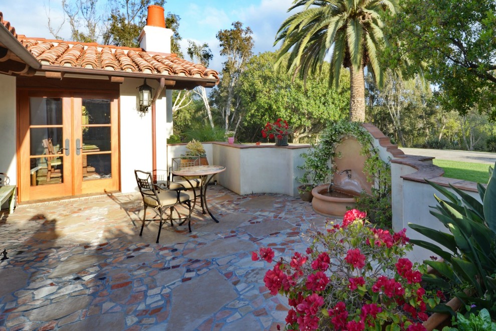 Imagen de patio mediterráneo extra grande sin cubierta en patio con fuente y adoquines de piedra natural
