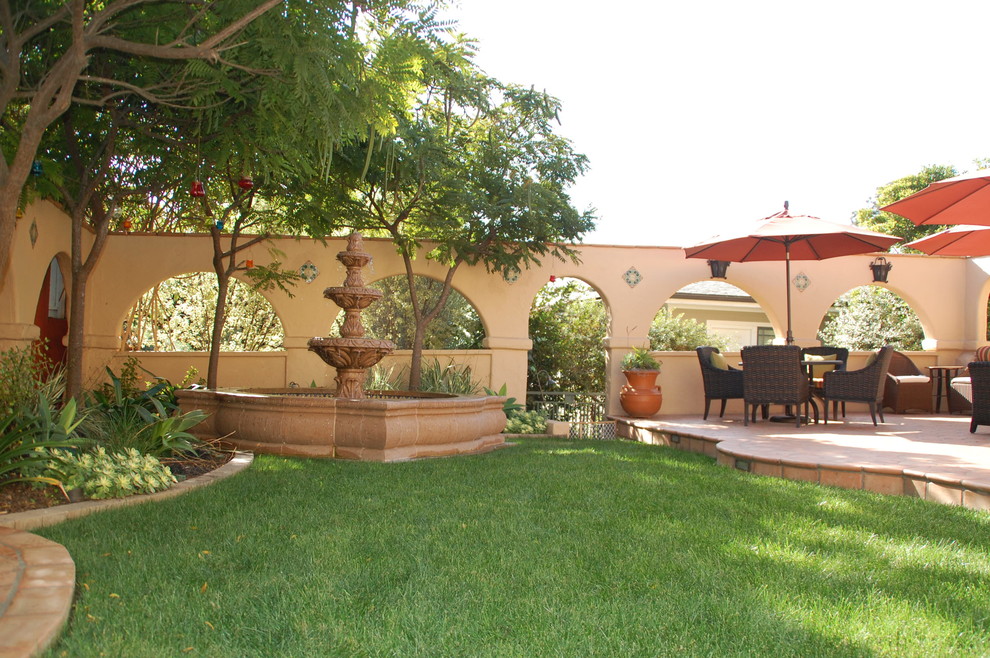 На фото: большой двор на заднем дворе в средиземноморском стиле с местом для костра и мощением клинкерной брусчаткой без защиты от солнца