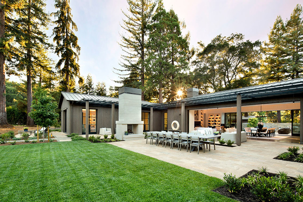 Idée de décoration pour une grande terrasse arrière champêtre avec un foyer extérieur et des pavés en pierre naturelle.