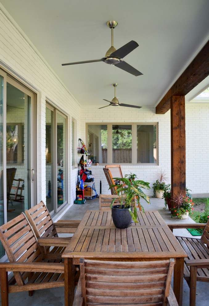 Cette image montre une terrasse arrière minimaliste avec une dalle de béton et une extension de toiture.